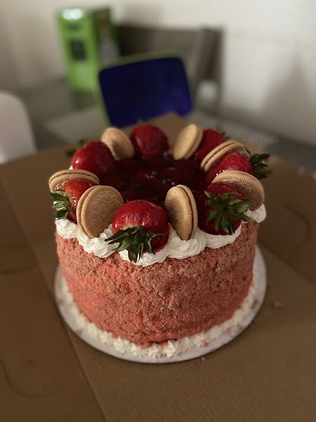 Strawberry crunch cake coated in pink cookie crumbs topped with fresh strawberries